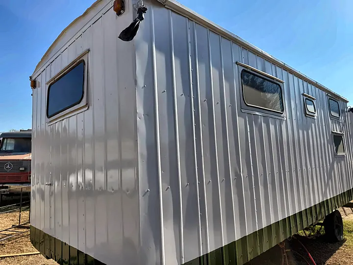 Casilla rural blanca con zócalo verde, dormitorio y comedor