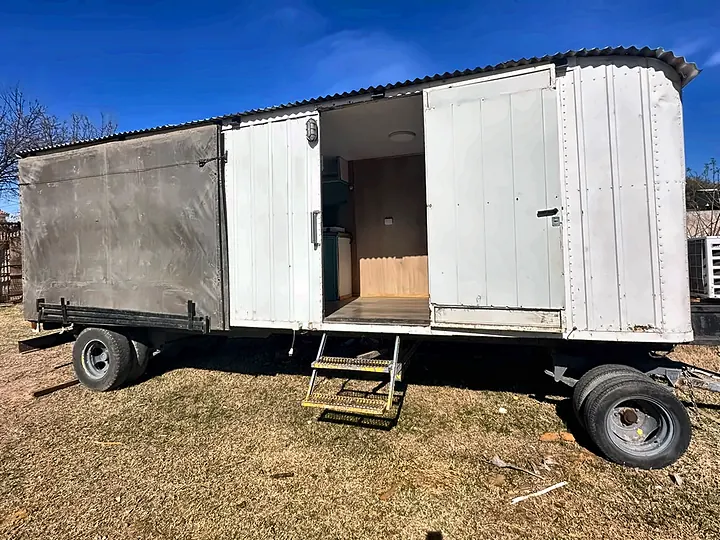 Casilla rural con baño, puertas abiertas y escalera de acceso